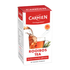 Carmién Rooibos Tea box with a glass of brewed rooibos tea and fresh rooibos sprigs, highlighting natural caffeine-free herbal tea.