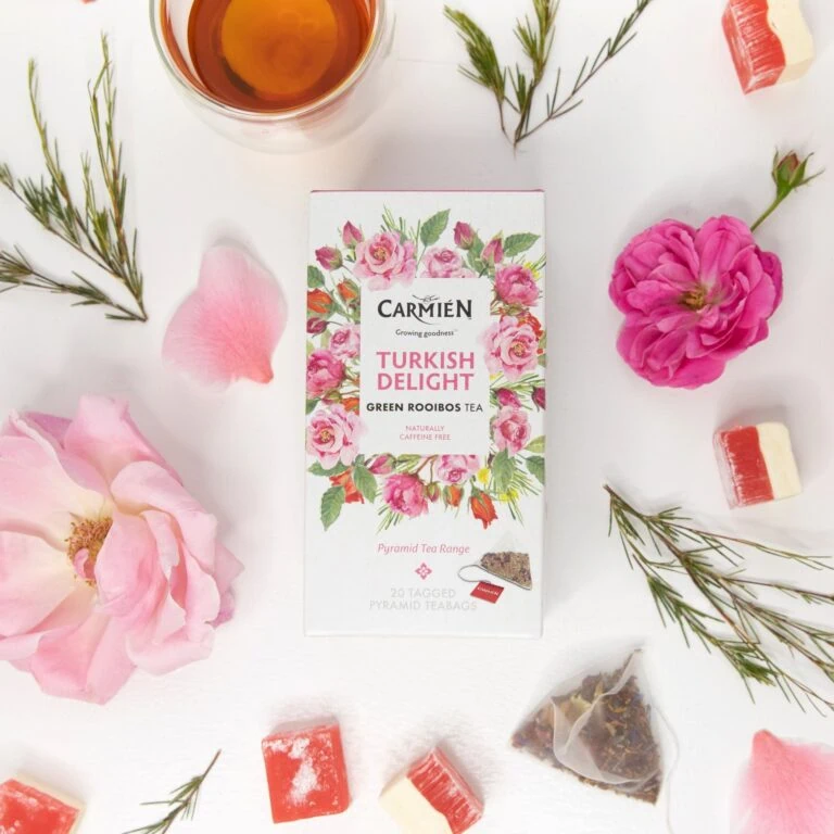 Carmién Turkish Delight Rooibos tea box with pyramid teabags surrounded by flowers and tea treats, highlighting the premium rooibos tea blend for e-commerce.