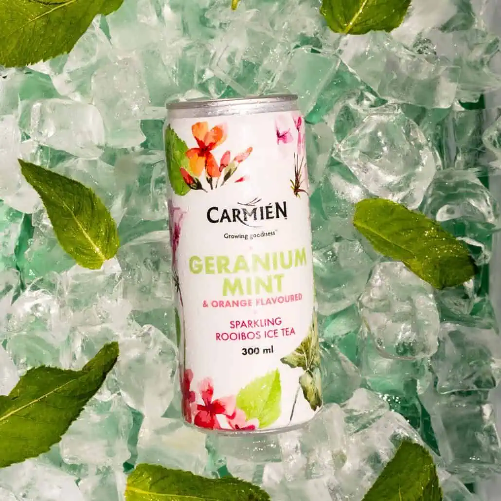 Geranium mint sparkling Rooibos ice tea in a 300ml can, surrounded by ice and fresh mint leaves, showcasing the natural and refreshing ingredients of Carmién Tea's botanical beverage with orange flavour.