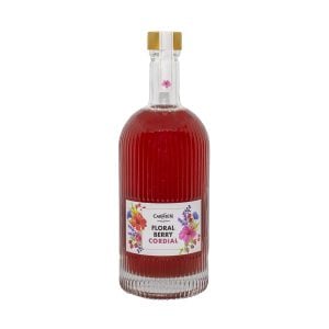 Rich red floral berry cordial in a clear, textured glass bottle with a gold and white cap and floral-themed label, ideal for enhancing wellness with natural Carmién Tea ingredients.
