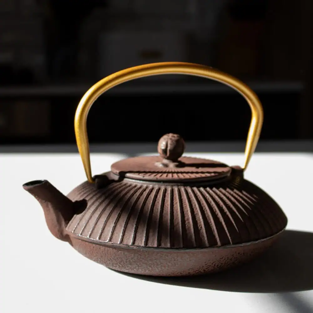 Elegant maroon and gold cast iron teapot for traditional tea brewing. Perfect for tea lovers seeking durability and style in their tea accessories.