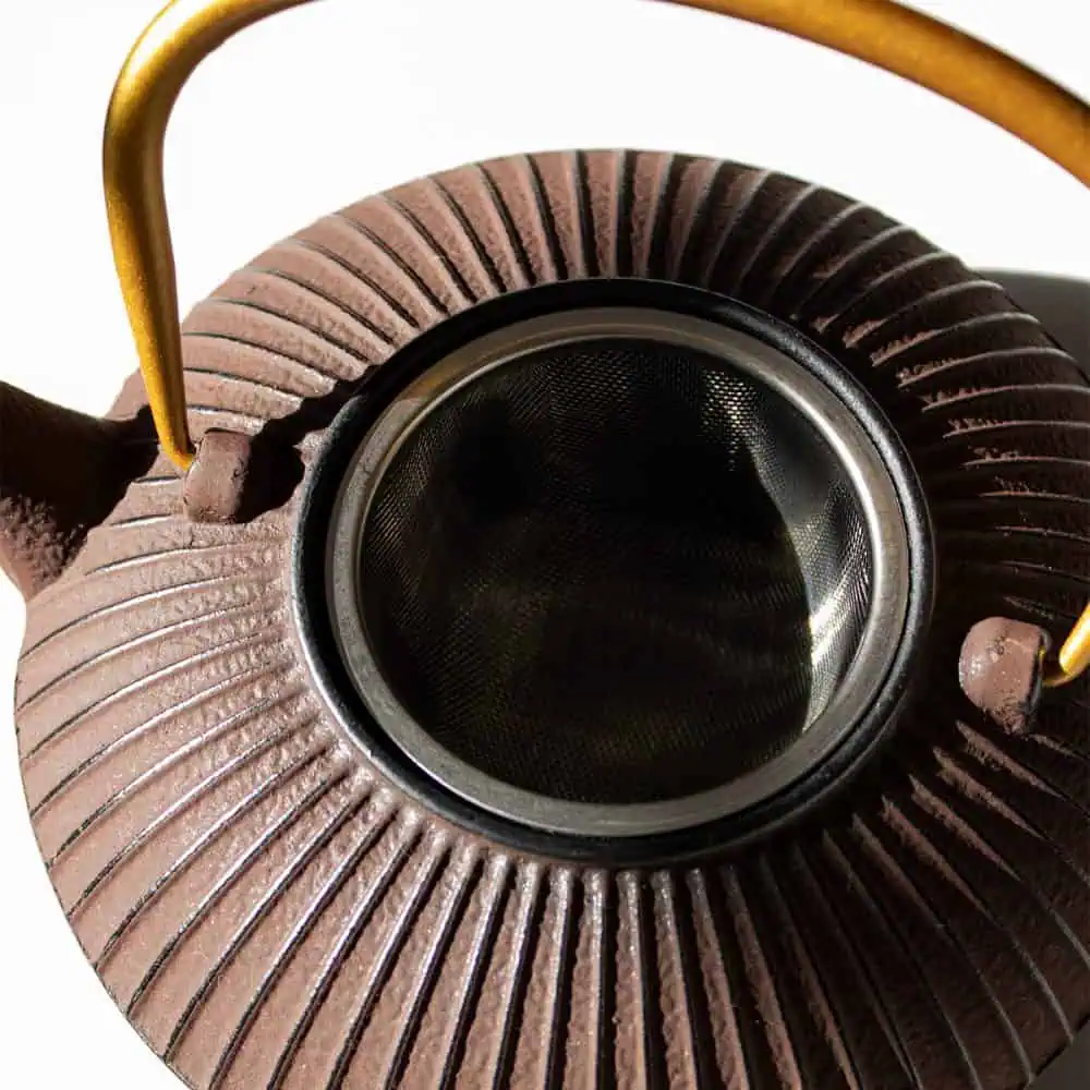 Elegant maroon and gold cast iron teapot with a textured surface, perfect for brewing and serving Carmién Tea. Durable and stylish, ideal for tea lovers who appreciate quality and tradition.