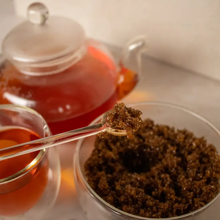 Rich Rooibos tea leaves and brewed herbal tea in glass teapot, traditional South African medicinal herbs display, natural wellness tea ingredients, Carmién Tea wellness products, antioxidant-rich herbal infusions for health-conscious consumers.