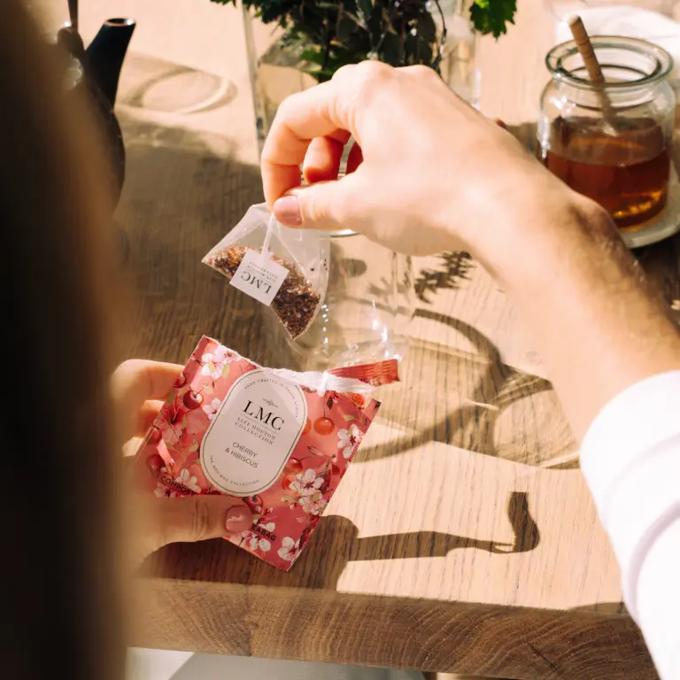 LMC Cherry & Hibiscus CarmiƩn Tea being prepared with dried herbs on a rustic wooden table in South Africa.