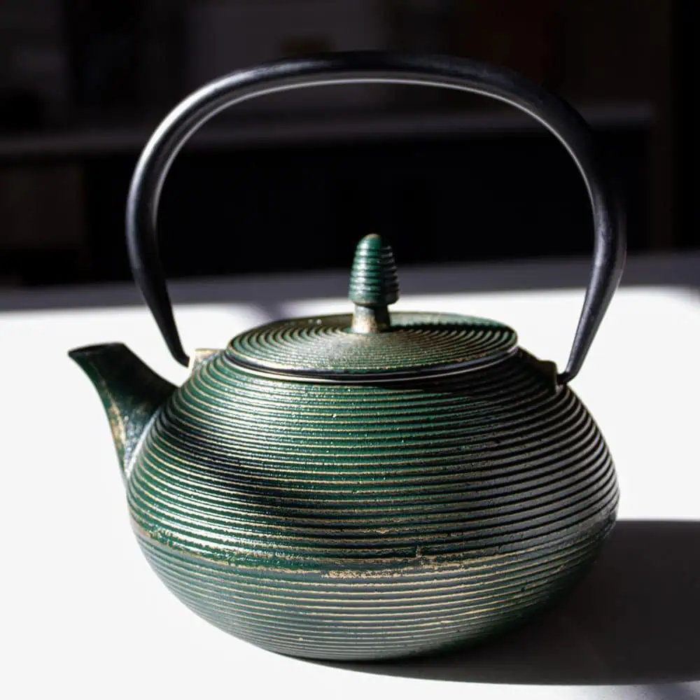 Elegant emerald green cast iron teapot with a black handle, perfect for brewing and serving traditional tea. Durable and stylish, ideal for tea enthusiasts.