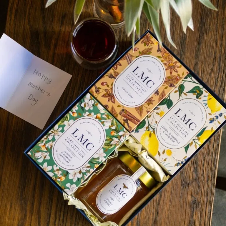 Elegant CarmiƩn Tea LMC gift box with honey and tea bags, perfect for gifting. Features vibrant floral packaging and a jar of honey, ideal for tea lovers.