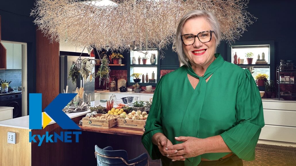 Elegant woman enjoying Carmién Tea in a cozy kitchen setting, highlighting the natural herbal tea brand.
