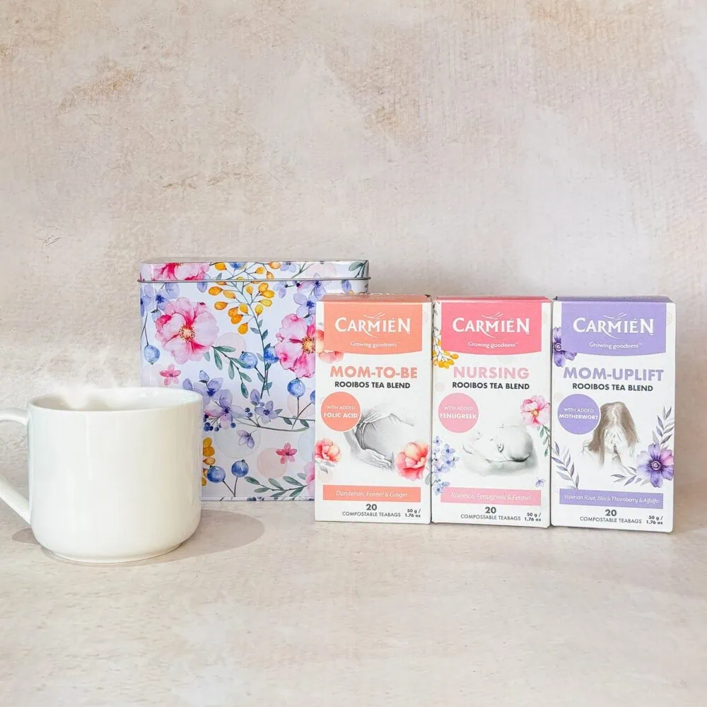 Carmién Rooibos Tea gift set with three tea boxes for Mom-to-Be, Nursing, and Mom-Uplift blends, displayed with a floral box and a white mug.