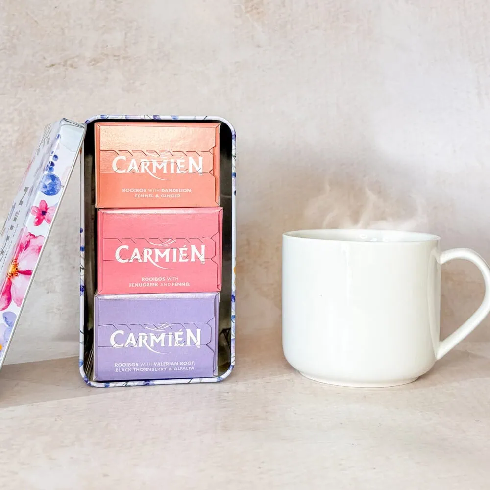 Carmién Rooibos tea gift box with three different flavoured tea bars and a steaming cup of rooibos tea on a light background.